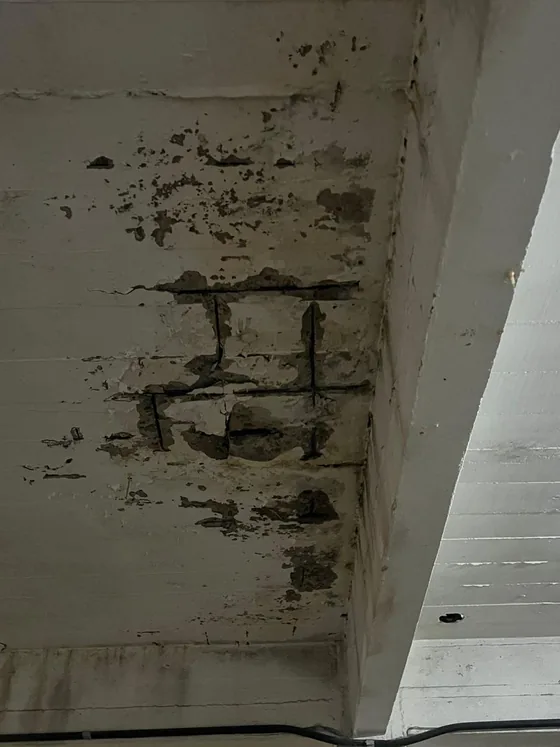 Teto do subsolo com concreto desplacado e armaduras de aço expostas e corroídas