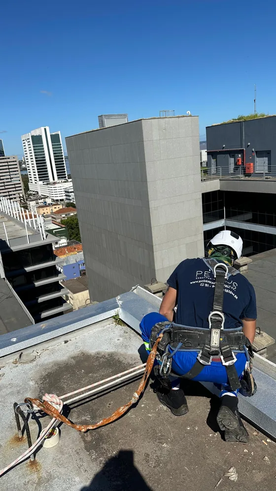 Profissional na cobertura do edifício preparando o ponto de ancoragem das cordas